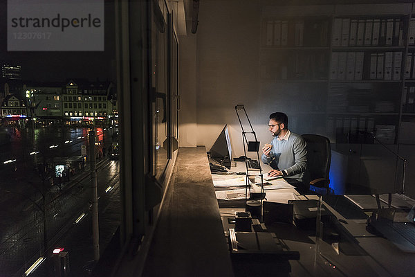 Geschäftsmann arbeitet nachts am Computer im Büro