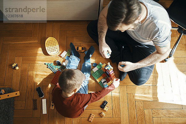 Vater und Sohn sitzen auf dem Boden und spielen mit Bausteinen  Draufsicht