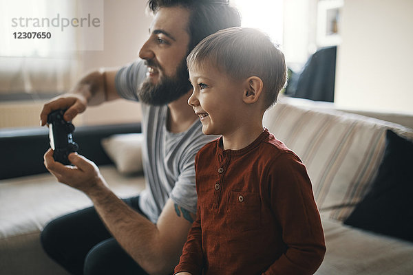 Glücklicher kleiner Junge beim Computerspiel mit seinem Vater zu Hause