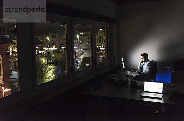 Geschäftsmann arbeitet nachts am Computer im Büro