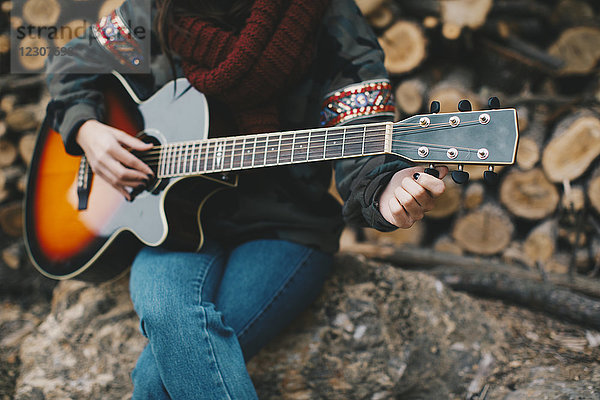 Junge Frau beim Gitarrespielen im Freien  Teilansicht