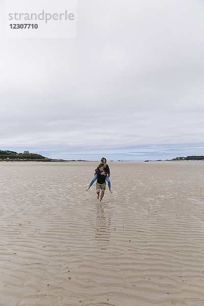 Frankreich  Bretagne  Guisseny  junger Mann mit Huckepack-Freundin am Strand