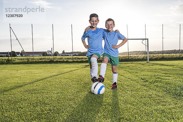 Lächelnde junge Fußballspieler umarmen sich auf dem Fußballplatz