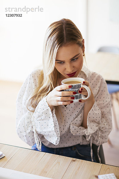 Junge Frau  die im Büro arbeitet  eine Pause macht  Kaffee trinkt