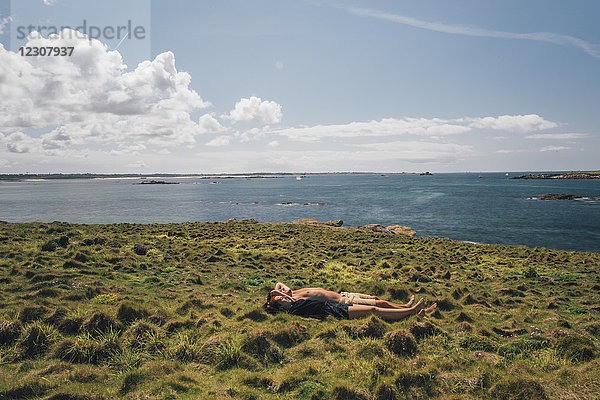 Frankreich  Bretagne  Landeda  Dunes de Sainte-Marguerite  junges Paar im Gras an der Küste liegend