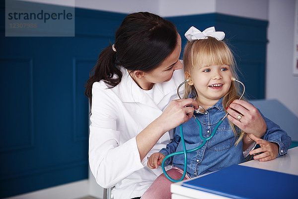 Arzt und Mädchen beim Spielen mit dem Stethoskop in der Praxis