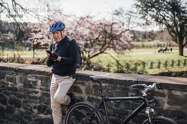 Senior Mann mit Fahrradhelm mit Smartphone