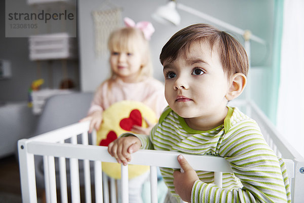 Portrait des Kleinkindes in der Krippe mit seiner Schwester im Hintergrund