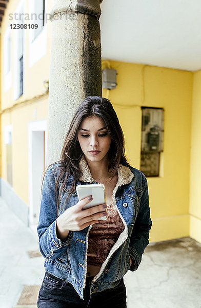 Junge Frau in einer Stadt  die ihr Smartphone überprüft.