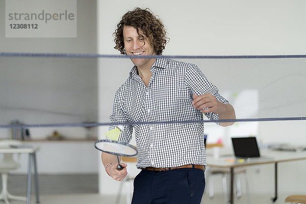 Geschäftsmann mit Spaß im Büro  Spielen mit Badmintonschläger und Federball