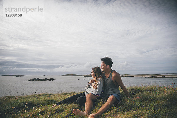 Frankreich  Bretagne  Landeda  Dunes de Sainte-Marguerite  liebevolles junges Paar an der Küste sitzend