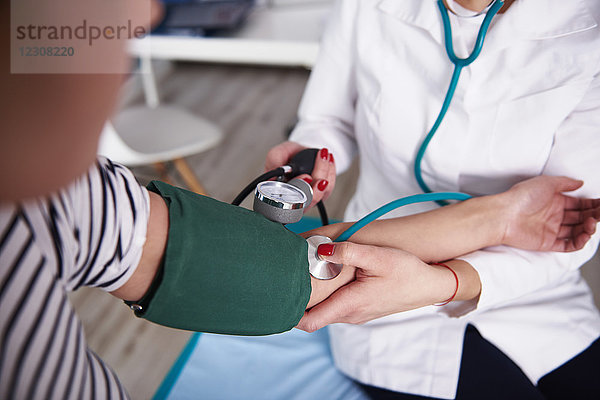 Arzt  der den Blutdruck der Frau in der Arztpraxis nimmt