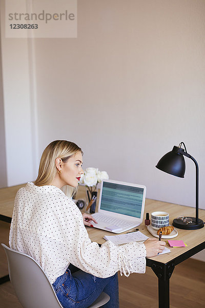 Blonde Geschäftsfrau am Schreibtisch sitzend  arbeitend