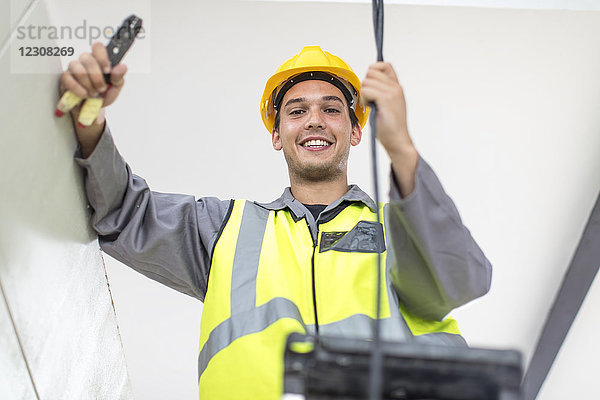 Porträt eines lächelnden Elektrikers auf der Baustelle