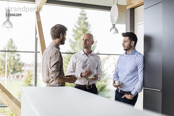Drei Geschäftsleute im Gespräch während der Kaffeepause