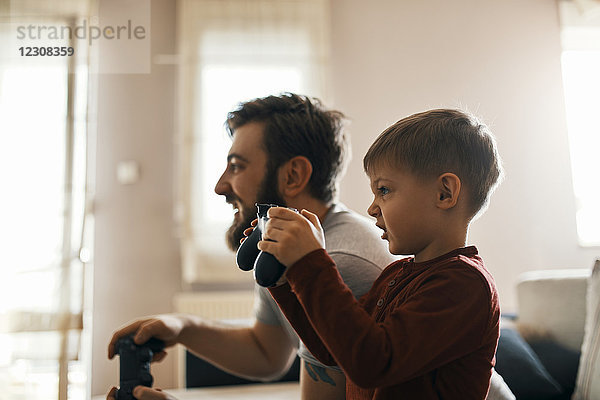 Kleiner Junge spielt Computerspiel mit seinem Vater zu Hause