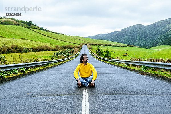 Azoren  Sao Miguel  Mann auf einer leeren Straße sitzend