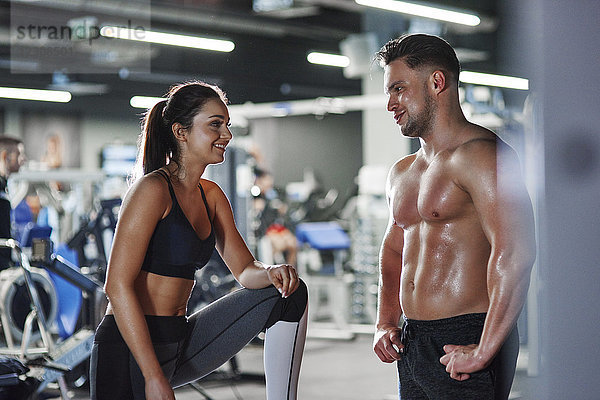 Lächelnder Mann und Frau reden im Fitnessstudio