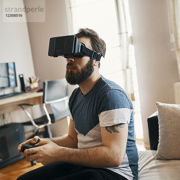 Mann mit Virtual-Reality-Brille zu Hause beim Computerspiel