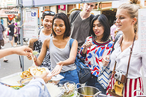 Thailand  Bangkok  Khao San Road  Gruppe von Freunden  die lokale Lebensmittel auf dem Straßenmarkt testen.
