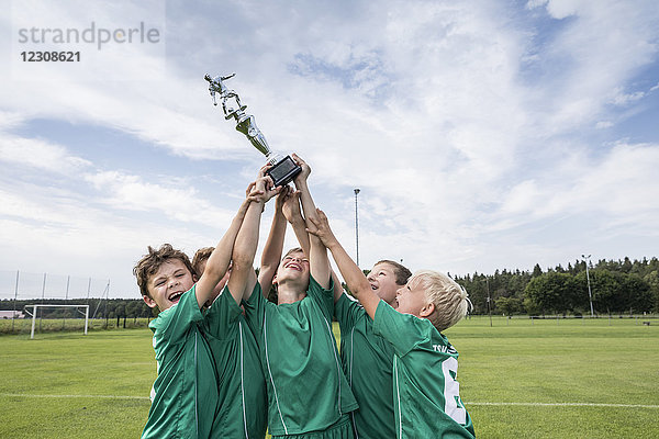 Junge Fußballspieler jubeln mit Pokal