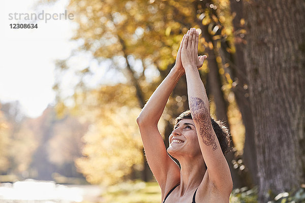 Lächelnde erwachsene Frau im Wald  die Yoga praktiziert.