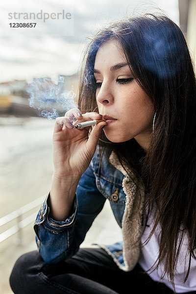 Junge Frau raucht eine Zigarette im Freien