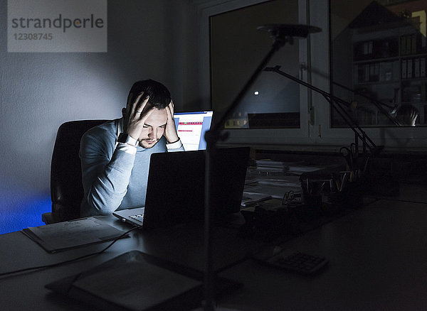Müde Geschäftsleute sitzen nachts im Büro am Schreibtisch