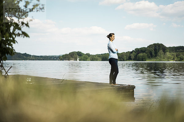 Frau steht auf einem Steg am See