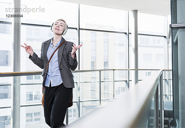 Frau im Bürobereich genießt Musik mit Kopfhörern