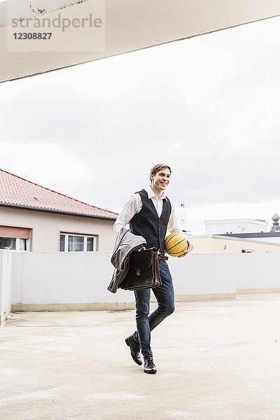 Lächelnder Geschäftsmann mit Basketball im Parkhaus