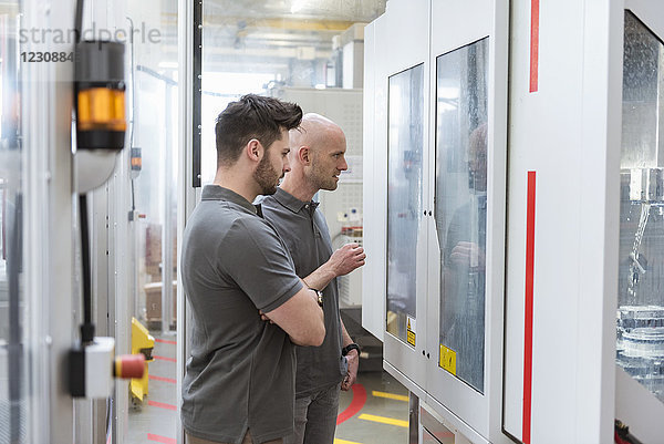 Zwei Männer untersuchen die Maschine in einer modernen Fabrik