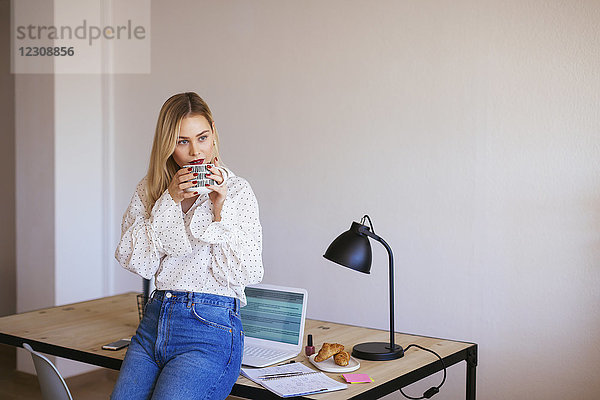Junge Frau  die im Büro arbeitet  eine Pause macht  Kaffee trinkt