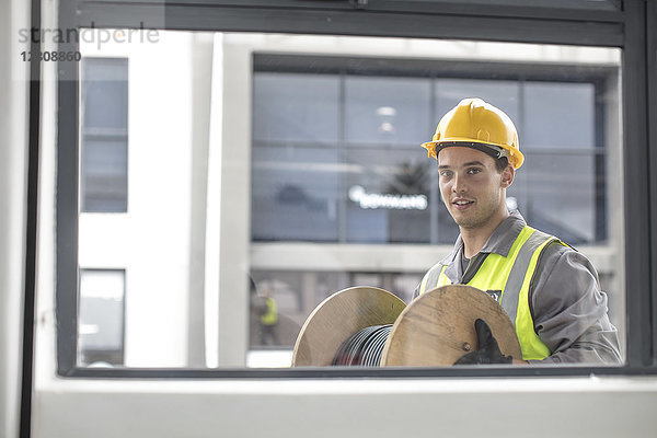 Portrait des Bauarbeiters mit Kabeltrommel