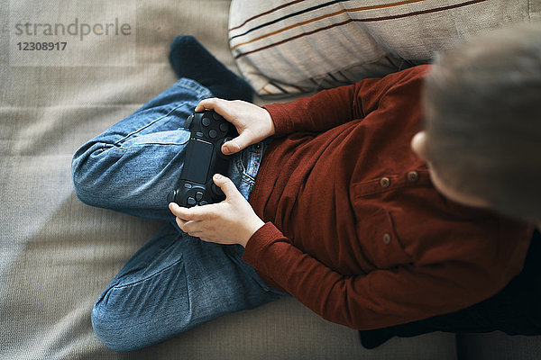 Kleiner Junge auf der Couch beim Computerspiel  Draufsicht