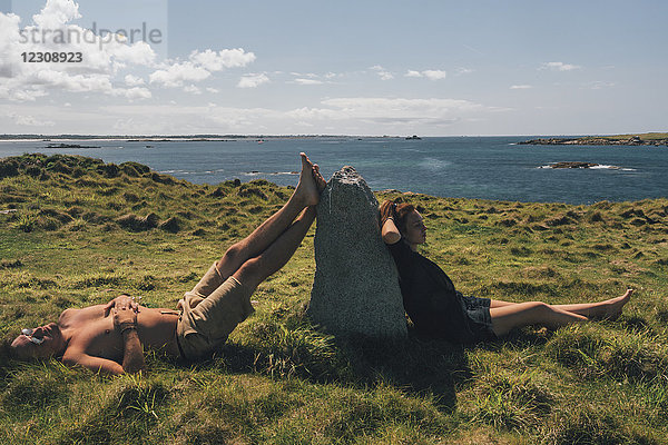 Frankreich  Bretagne  Landeda  Dunes de Sainte-Marguerite  junges Paar entspannt im Gras an der Küste