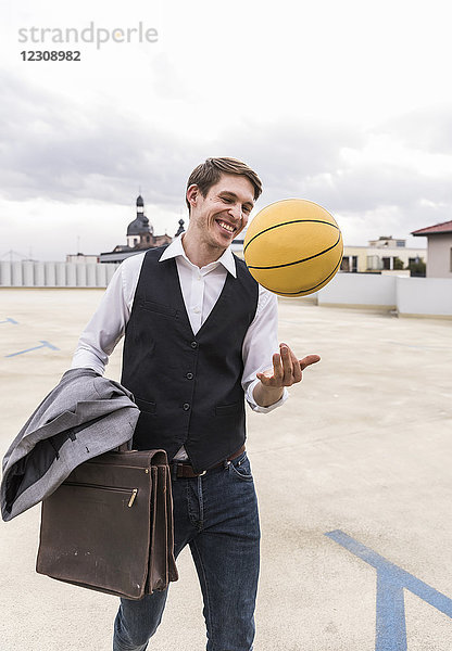 Glücklicher Geschäftsmann mit Basketball im Parkhaus