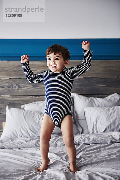 Porträt eines glücklichen Kleinkindes beim Springen auf dem Bett