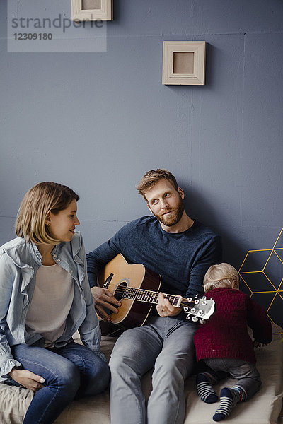 Glückliche Familie  die mit ihrem Sohn zu Hause Musik spielt.