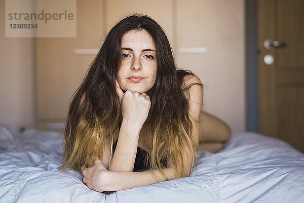 Porträt einer jungen Frau auf dem Bett liegend