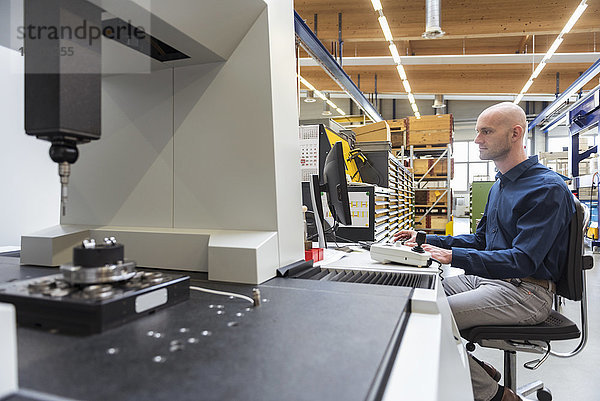 Mensch mit Computer an der Maschine in der modernen Fabrik