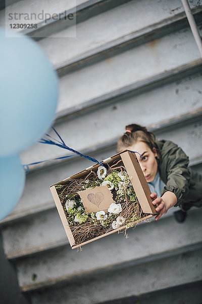 Frau schickt Geschenk im Karton mit Luftballons
