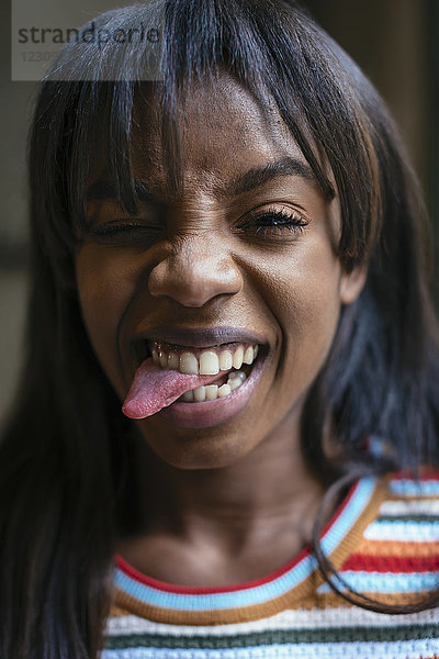 Porträt einer lachenden jungen Frau  die die Zunge herausstreckt.