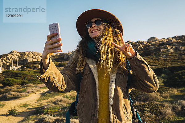 Italien  Sardinien  glückliche Frau auf einer Wanderung mit einem Selfie