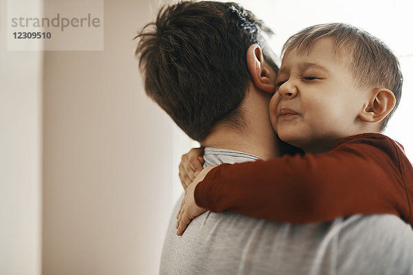 Porträt eines Kleinkindes  das seinen Vater umarmt