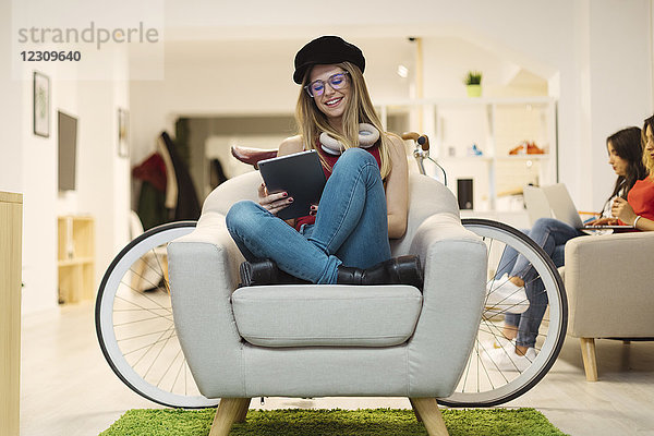 Lässige junge Frau mit Tablette im Coworking Space