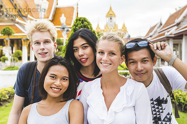 Thailand  Bangkok  Gruppenbild von fünf Freunden beim Besuch des Tempelkomplexes