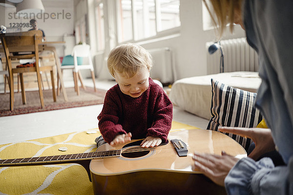Kleiner Junge erkundet mit seiner Mutter eine Gitarre