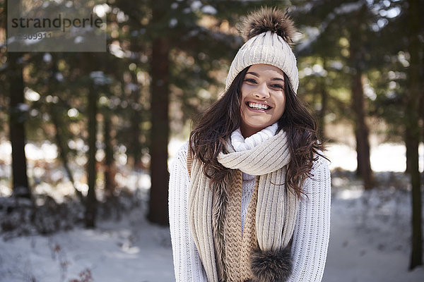 Porträt einer lachenden jungen Frau in Strickwaren im Winterwald