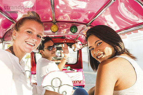 Thailand  Bangkok  Portrait von lächelnden Freunden beim Tuk-Tuk-Reiten